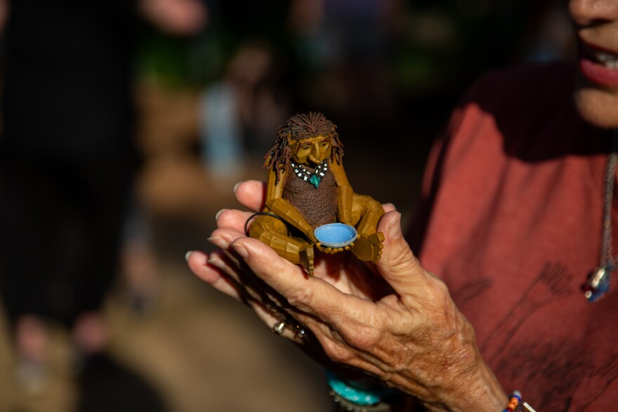 A woman holds a small troll sculpture.