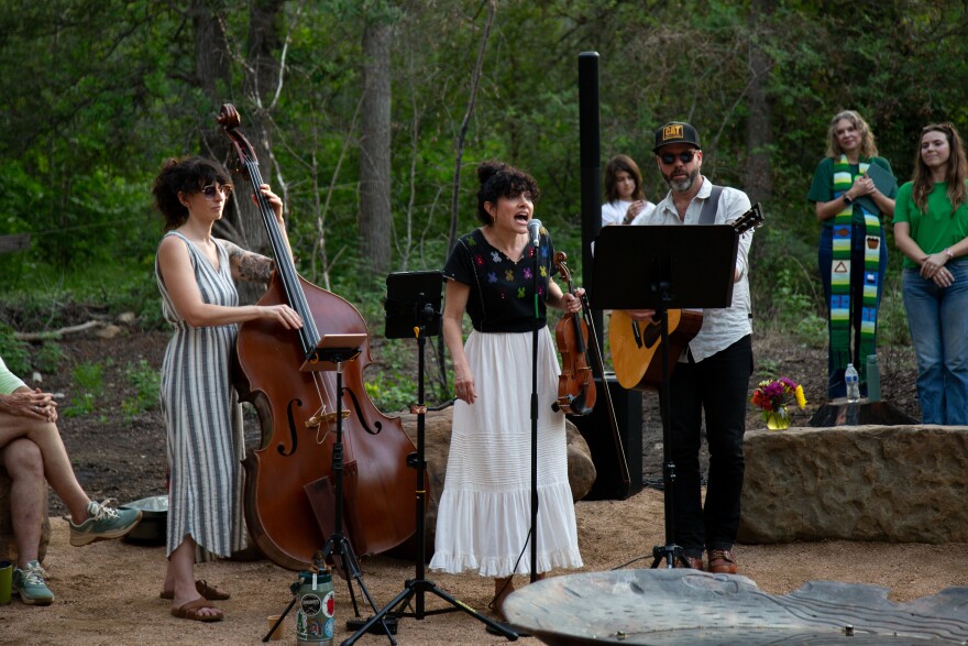 A band with a female singer plays outside at a park.