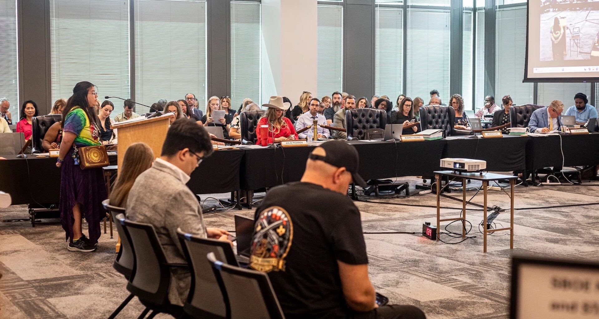 A photo of a woman speaking to the board form a podium.