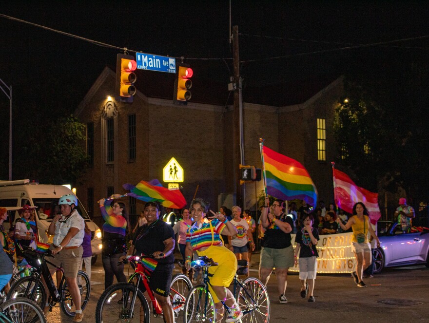 People dressed in pride colors bike onto the Pride Parade.