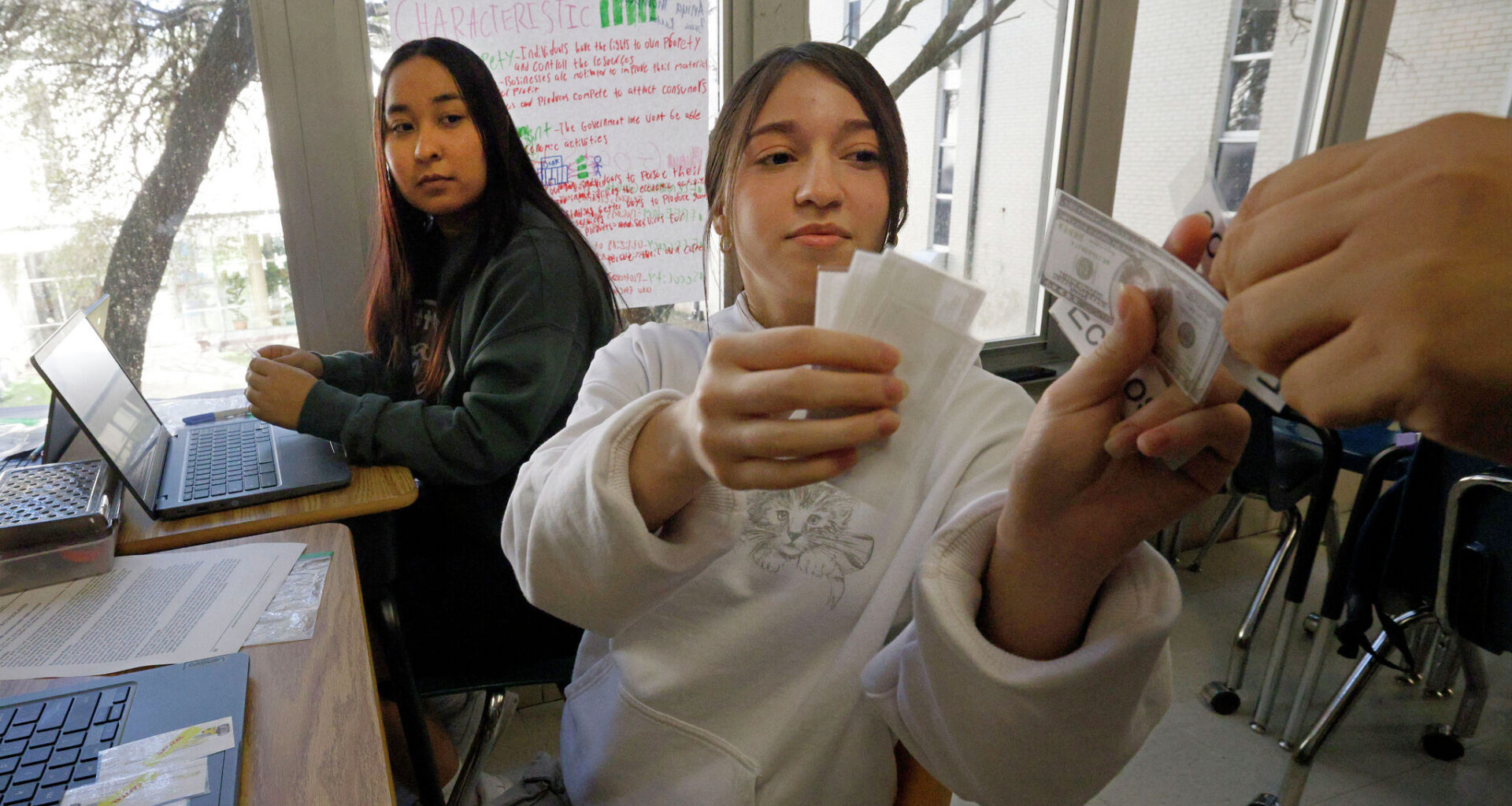Eleventh grader Arlyn Orellana (right) role-plays with her classmate to analyze real-world economic concepts as classmate Alexandra Luna looks on during a personal financial literacy class at Skyline High School on  March 12, 2026, in Dallas.