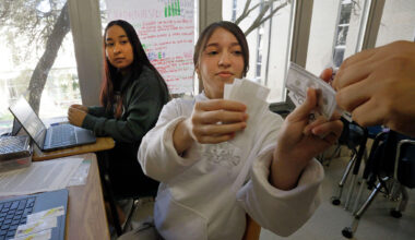 Eleventh grader Arlyn Orellana (right) role-plays with her classmate to analyze real-world economic concepts as classmate Alexandra Luna looks on during a personal financial literacy class at Skyline High School on  March 12, 2026, in Dallas.