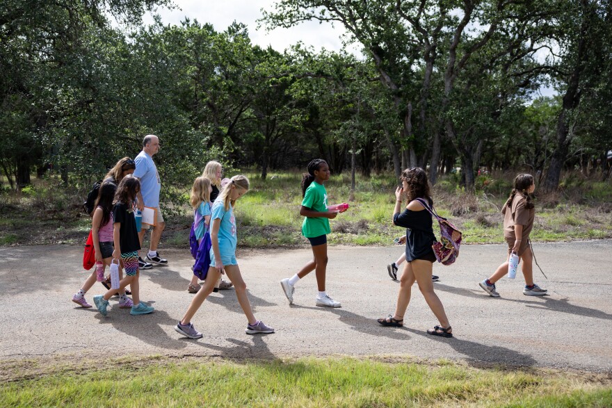 Children and an adult walk along a road in a nature area.