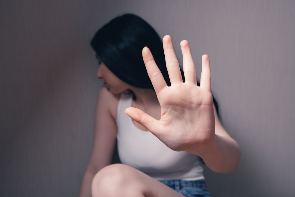 woman in white tank top covering face with her hands