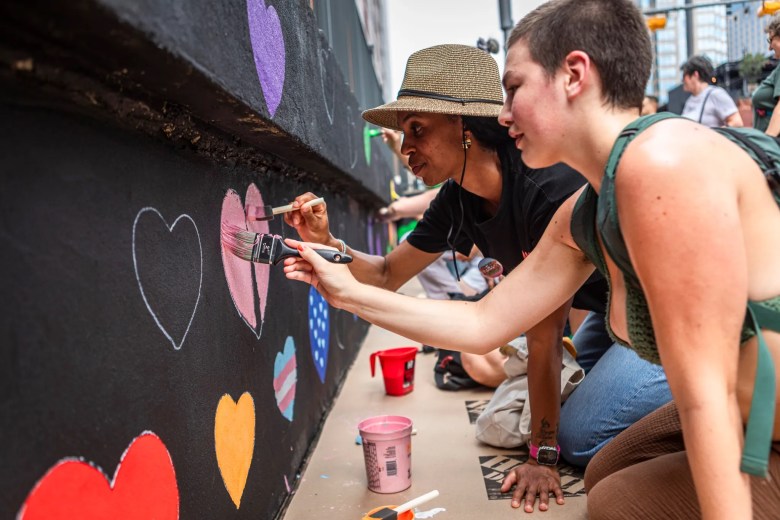 Attendees paint in hearts on a new mural on 4th Street on June 20, 2026 to commemorate the spot where the rainbow crosswalk will soon be removed in Austin. The removal comes after the Texas Department of Transportation issued a letter to remove any artwork on roadways.