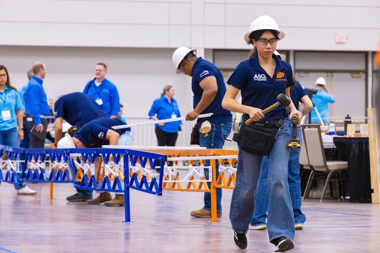 Yesenia Carmona, a junior civil engineering major at The University of Texas at El Paso, carries tools to her team during the assembly phase of the 2026 Student Steel Bridge Competition National Finals on May 22. For the first time, the UTEP Miguel A. Loya College of Engineering served as host of the prestigious annual competition, which challenges students to design, fabricate and construct a scale steel bridge while demonstrating technical expertise, teamwork and efficiency under real-world engineering constraints.