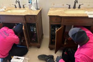 Two licensed plumbers perform under sink drain cleaning on twin vanities in Plano, TX home, Mother Modern Plumbing