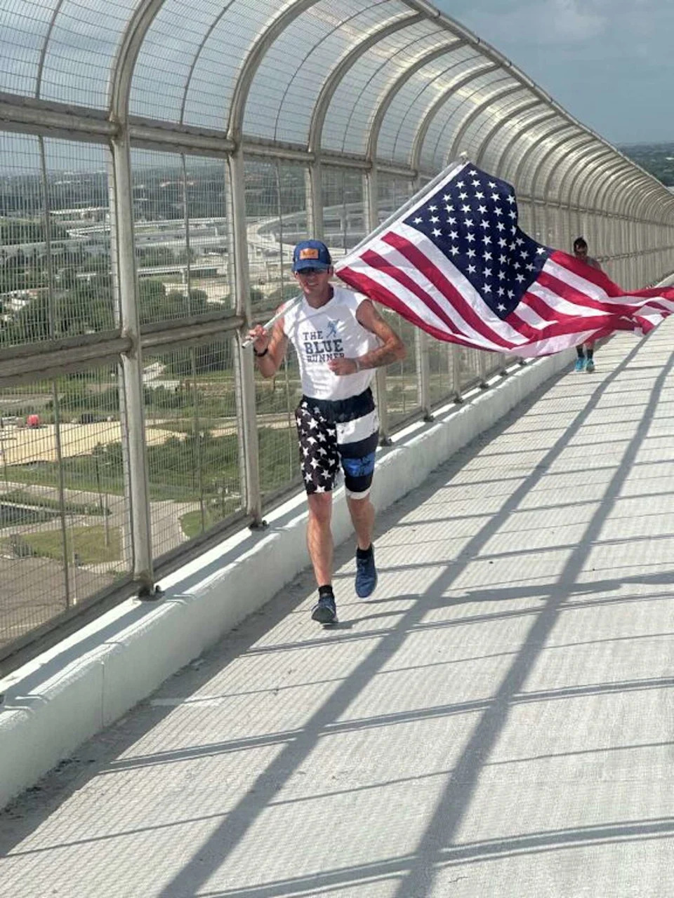 A runner carrying an American flag crosses the new Corpus Christi Harbor Bridge during the grand opening of the bridge's shared-use path in 2025. The bridge has been named the scariest in Texas, according to a new survey of more than 3,000 cyclists across the country. (Courtesy Harbor Bridge and TxDOT)