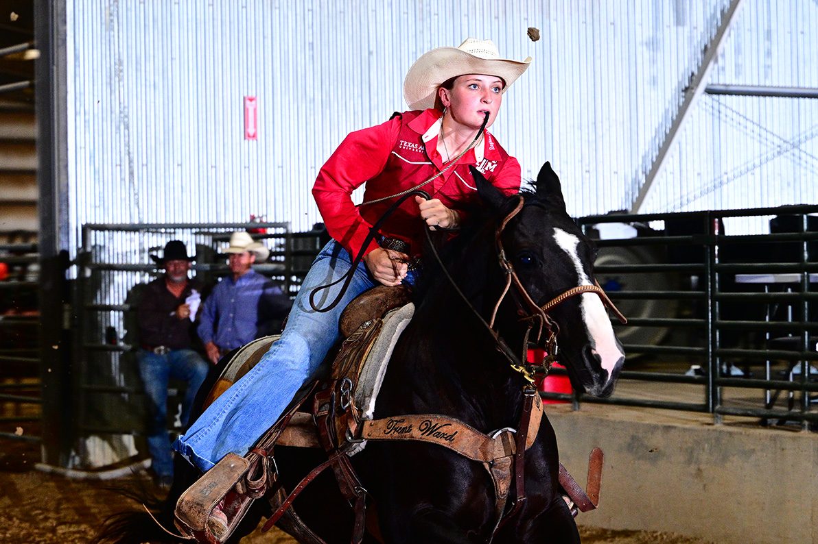 a woman riding a horse holds a tie string in her mouth while she rides