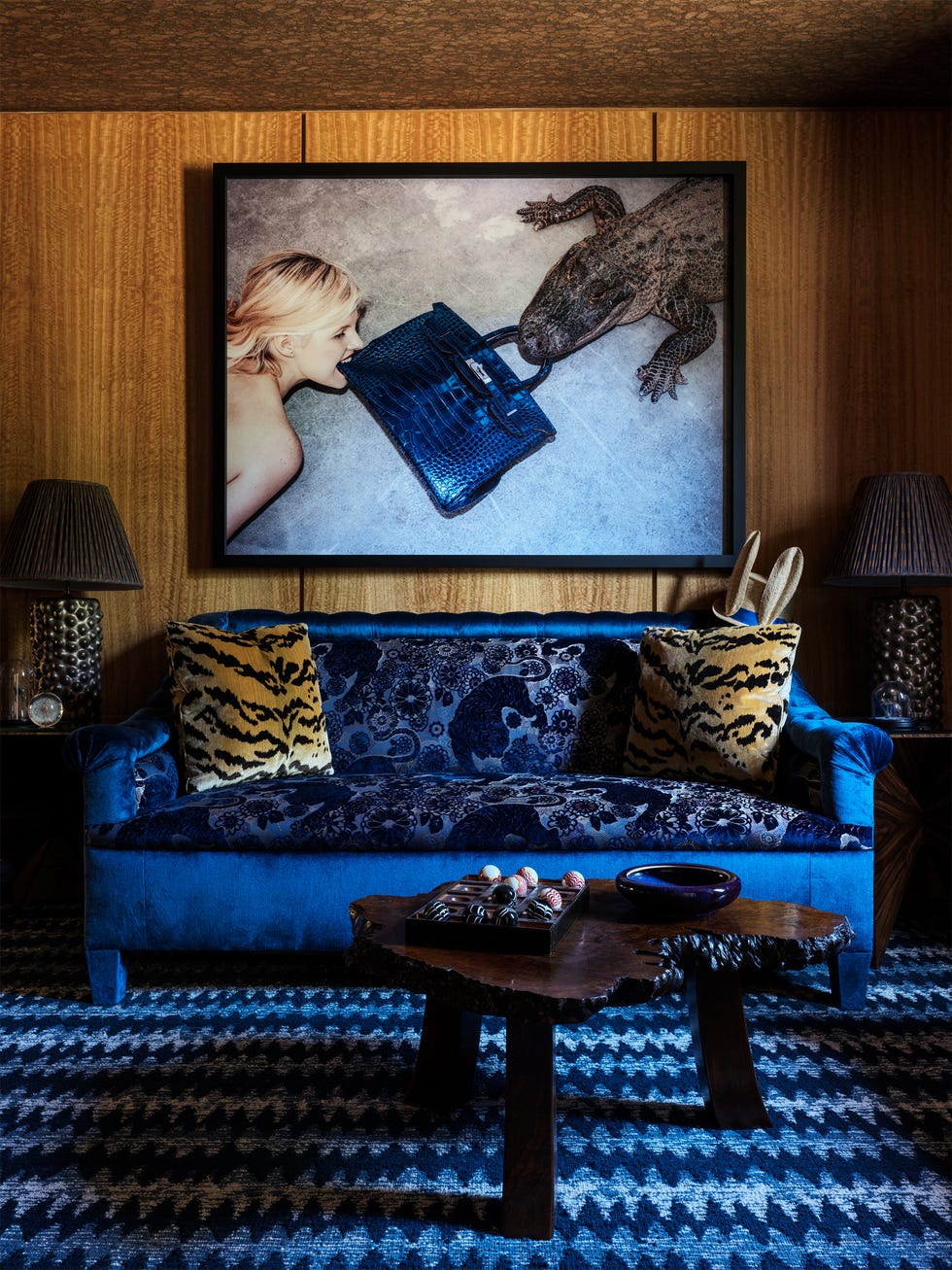 Eclectic living room with blue velvet sofa and large framed art above.