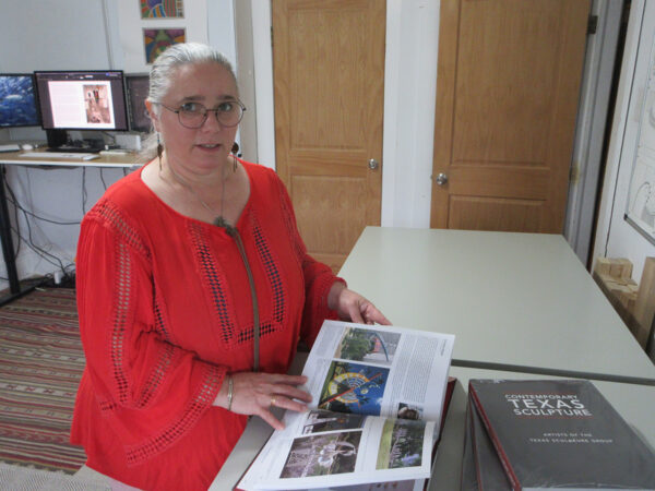 A woman stands at a counter with an open book.