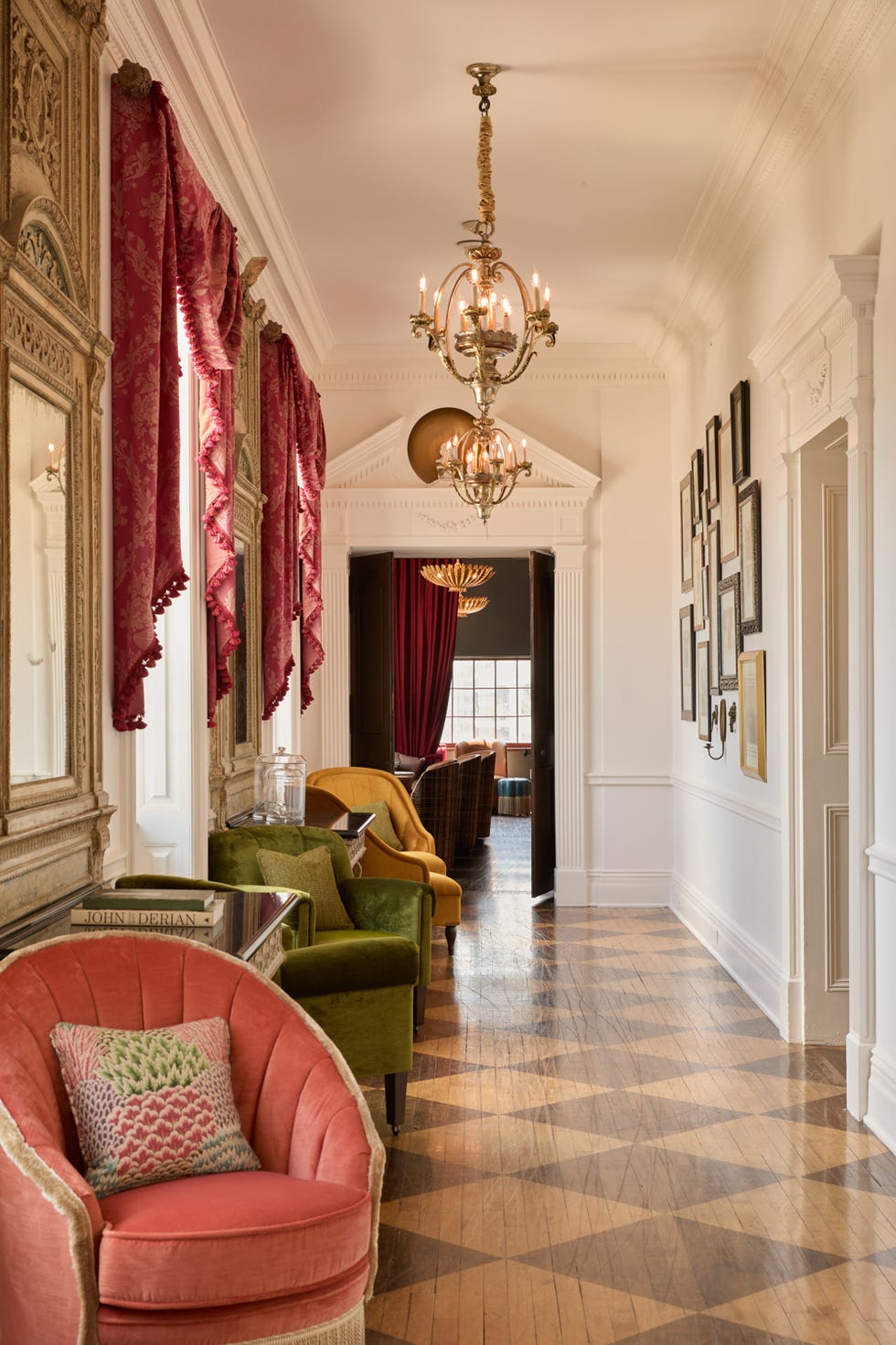 Elegant hallway with red curtains, vintage chandeliers, and colorful armchairs.