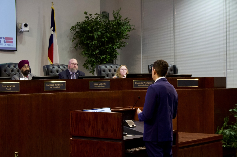 a man speaking to people at a dais