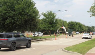 A gray SUV drives past a section of road under construction
