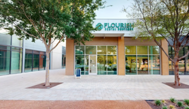 An exterior view of a building with a sign reading "Flourish Dental Boutique" in teal letters