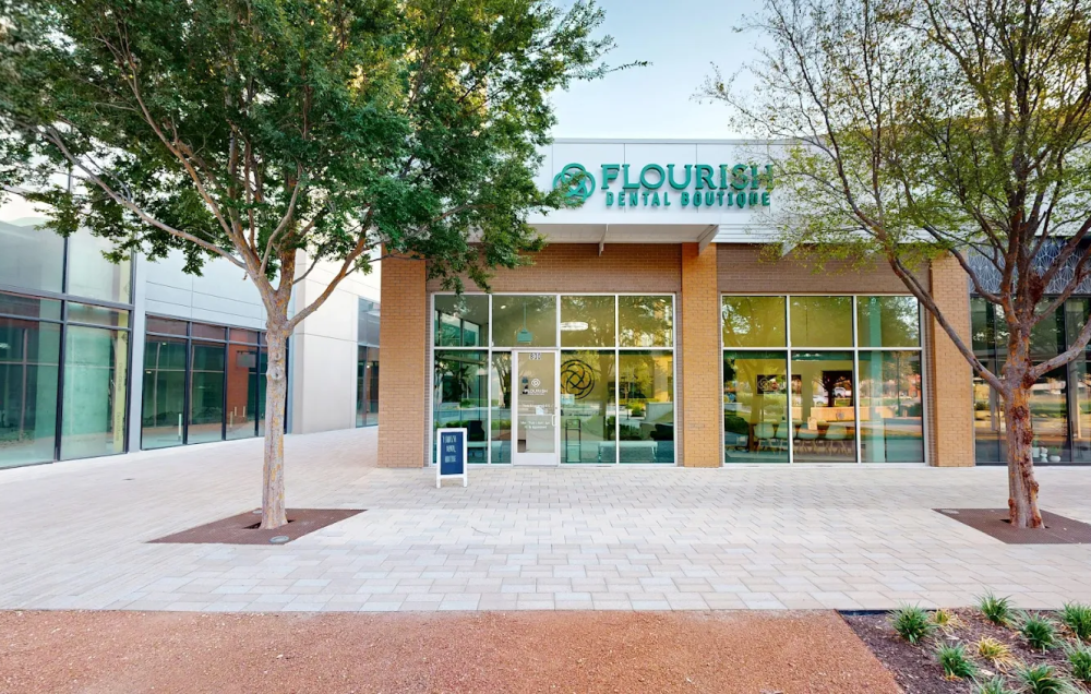 An exterior view of a building with a sign reading "Flourish Dental Boutique" in teal letters