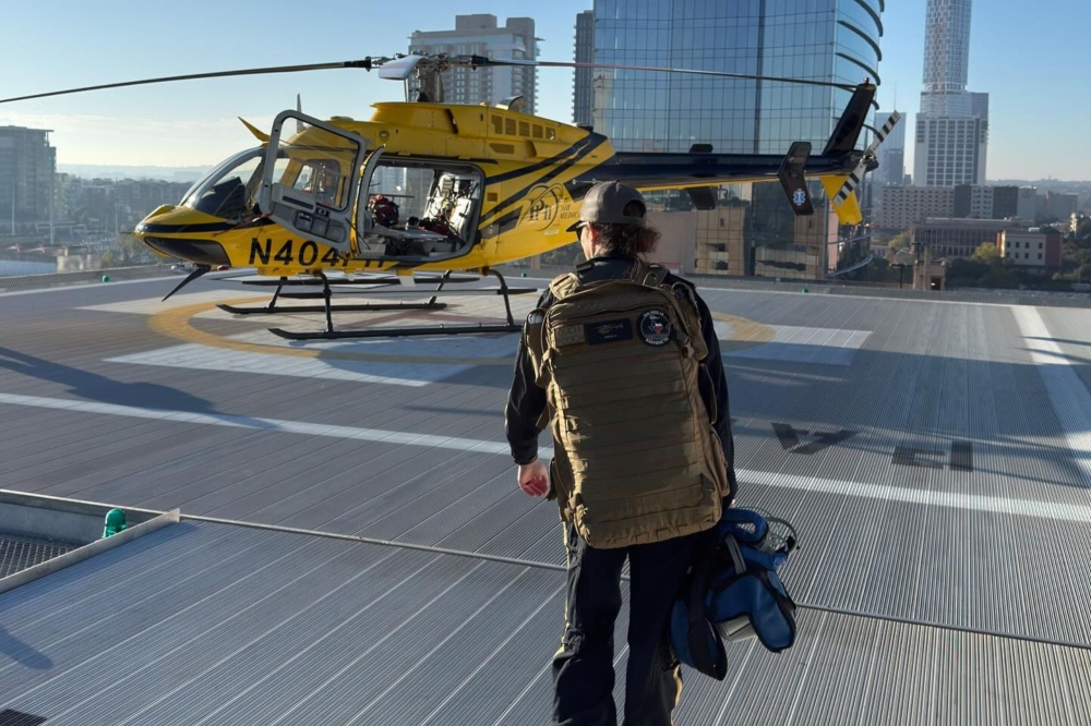 A PHI Air Medical crew member walks toward a helicopter on a rooftop helipad. (Courtesy PHI Air Medical)