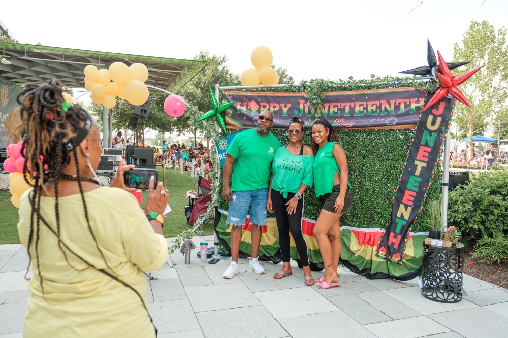 Woman taking a photo of a family during a Juneteenth celebration at Redemption Square