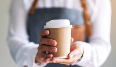 A waiter holding a cup of coffee, the cup has a sleeve around it