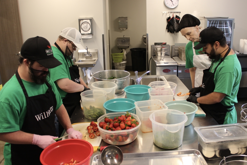 Nolan Stilwell, William Mullican IV and Eric Hernandez cut strawberries and peppers to make Texas Sweet Heat Jam with help from Christine Stilwell. (Daniel Schwalm/Community Impact)