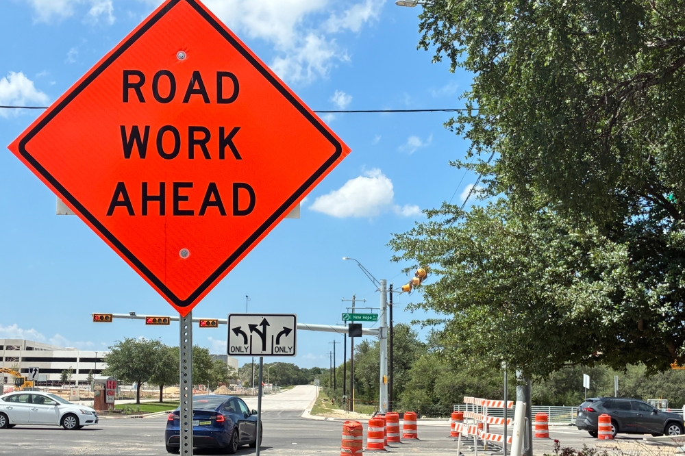 Orange construction barrels and a sign alert drivers to ongoing lane changes at New Hope Drive, where the city is expanding the roadway from four to six lanes and building an innovative intersection at 183A Toll. (Jessica McLaren/Community Impact)