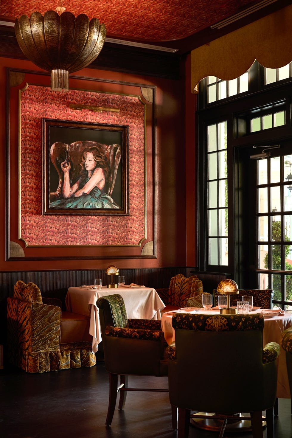 Cozy restaurant corner with elegant decor, framed painting, and plush seating under soft lighting.