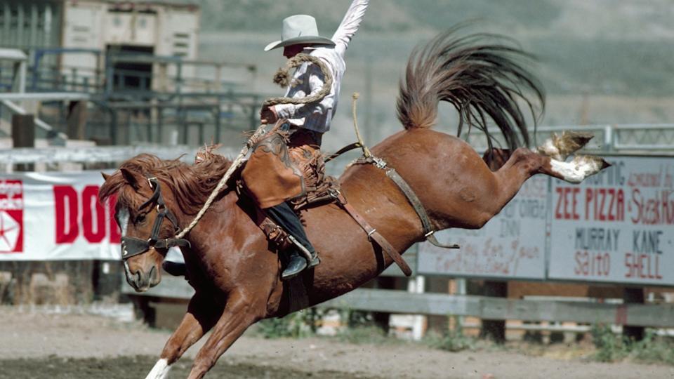 A man holding onto a bucking bronco