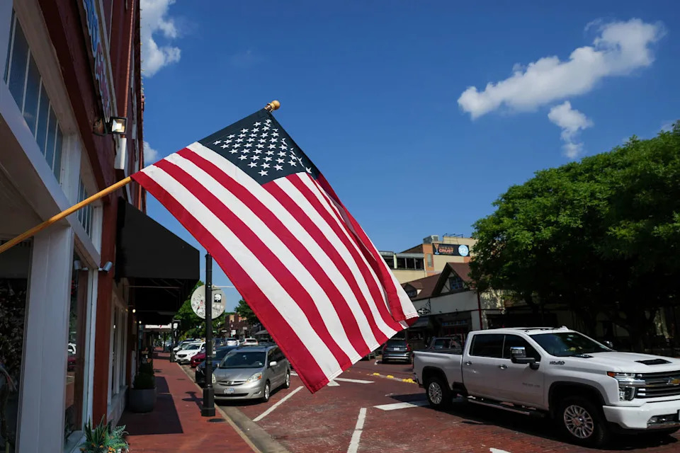 Traffic on E. 15th Street passes a flag on Wednesday, May 31, 2023, in Downtown Plano. (Smiley N. Pool/Dallas Morning News)