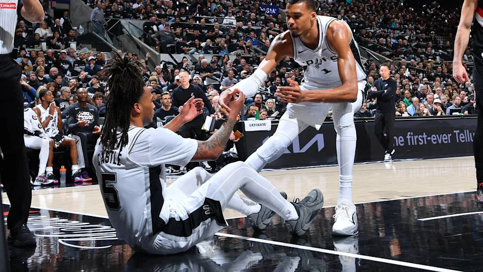 <a class="link " href="https://sports.yahoo.com/nba/players/10290/" data-i13n="sec:content-canvas;subsec:anchor_text;elm:context_link" data-ylk="slk:Stephon Castle;sec:content-canvas;subsec:anchor_text;elm:context_link;itc:0" data-yga="{"yLinkElement":"context_link","yModuleName":"content-canvas","yLinkText":"Stephon Castle","ySubModuleName":"anchor_text","yHasCommerce":false}">Stephon Castle</a> #5 is helped up by <a class="link " href="https://sports.yahoo.com/nba/players/10094/" data-i13n="sec:content-canvas;subsec:anchor_text;elm:context_link" data-ylk="slk:Victor Wembanyama;sec:content-canvas;subsec:anchor_text;elm:context_link;itc:0" data-yga="{"yLinkElement":"context_link","yModuleName":"content-canvas","yLinkText":"Victor Wembanyama","ySubModuleName":"anchor_text","yHasCommerce":false}">Victor Wembanyama</a> #1 of the San Antonio Spurs against the <a class="link " href="https://sports.yahoo.com/nba/teams/portland/" data-i13n="sec:content-canvas;subsec:anchor_text;elm:context_link" data-ylk="slk:Portland Trail Blazers;sec:content-canvas;subsec:anchor_text;elm:context_link;itc:0" data-yga="{"yLinkElement":"context_link","yModuleName":"content-canvas","yLinkText":"Portland Trail Blazers","ySubModuleName":"anchor_text","yHasCommerce":false}">Portland Trail Blazers</a> during Round One Game Two of the 2026 NBA Playoffs on April 21, 2026 at the Frost Bank Center in San Antonio, Texas. <p>&lpar;Photos by Michael Gonzales&sol;NBAE via Getty Images&rpar;</p>