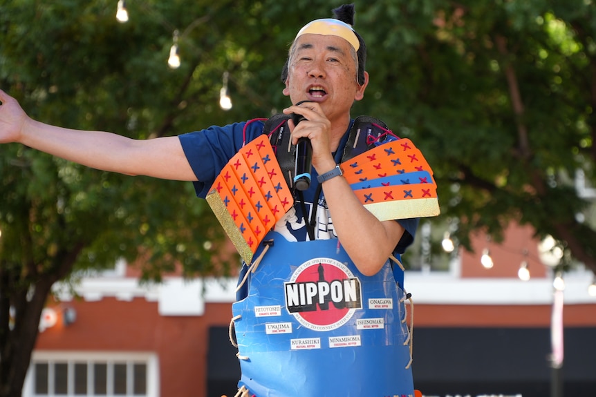 A Japanese man with cardboard orange and blue 'armour'.