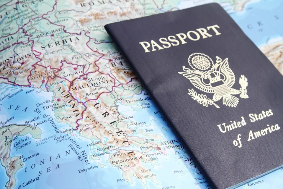 Stock image shows a US passport on a map of Greece and other south eastern European countries, including Albania, Serbia, Macedonia, Montenegro, and Kosovo.