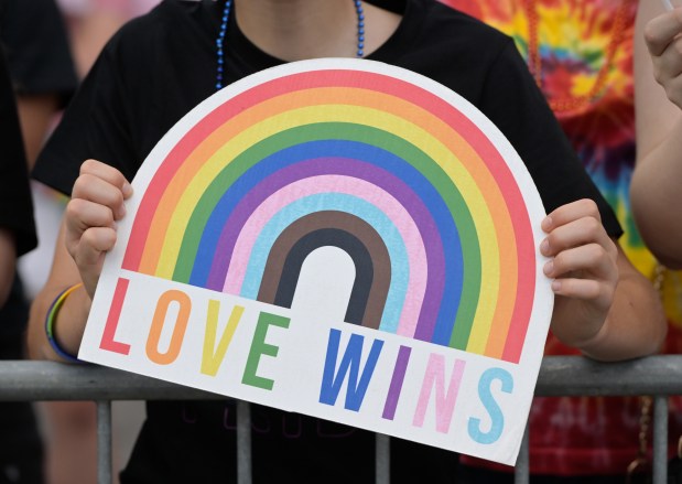 A parade goer holds a "Love Wins" sign during the annual Pride Parade in downtown Aurora on Sunday, June 14, 2026. (Mark Black / for the Beacon-News)