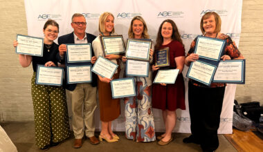 a group of people holding many award certificates and plaques