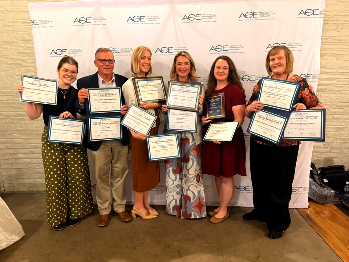 a group of people holding many award certificates and plaques