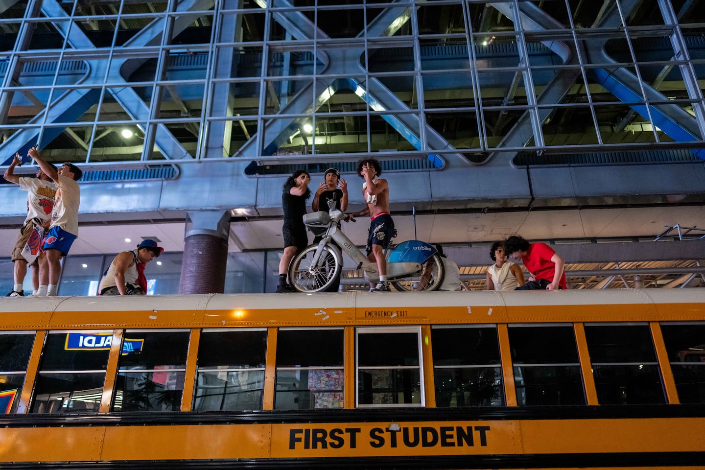 New York Knicks fans  sit on a citibike on top of a school bus as they celebrate after they win the NBA Finals in Times Square on June 14, 2026 in New York City. The New York Knicks lead the San Antonio Spurs 3-1 and could win the franchise's first NBA championship since 1973 if they win tonight.