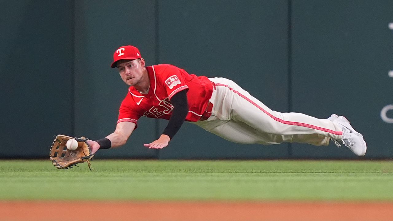 Texas Rangers left fielder Jarred Kelenic dives to catch a fly ball hit by San Diego Padres Jackson Merrill during the sixth inning of a baseball game, Saturday, June 20, 2026, in Arlington, Texas. (AP Photo/LM Otero)