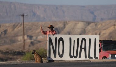 Shawn McQuire holds a sign in opposition to the border wall in the Texas Big Bend region near Terlingua, Texas, Wednesday, March 18, 2026. (AP Photo/LM Otero)