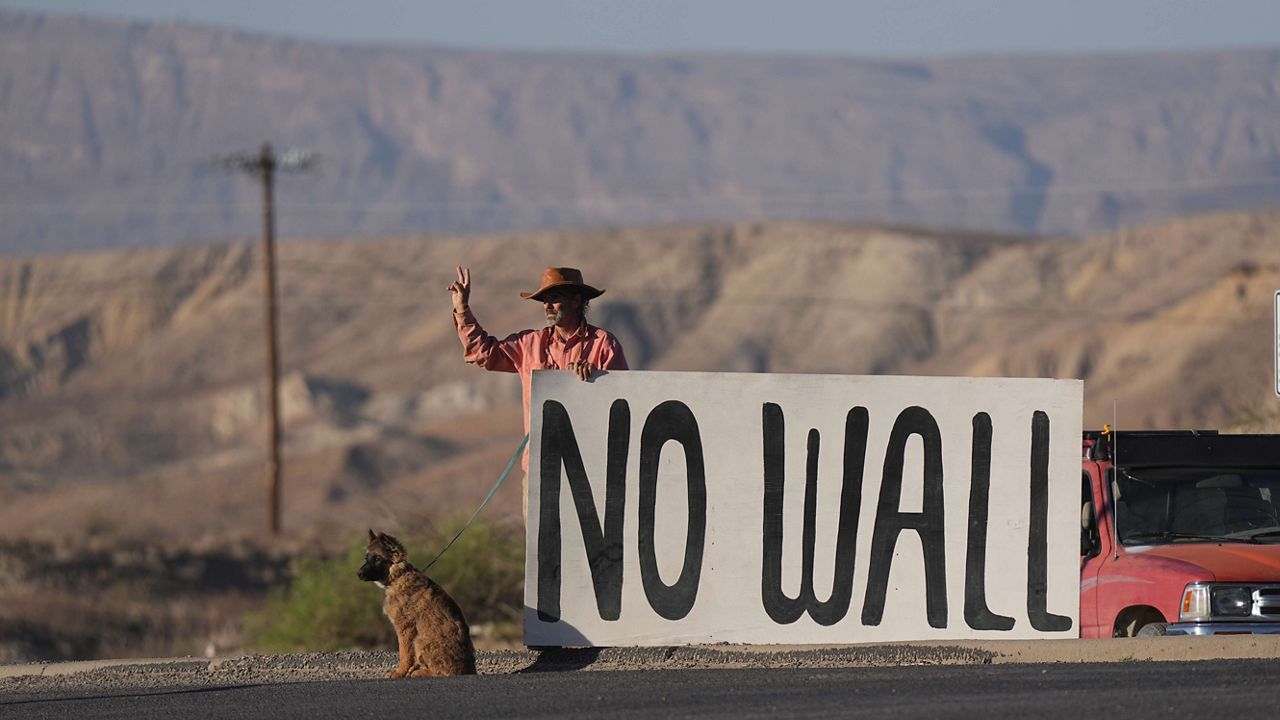 Shawn McQuire holds a sign in opposition to the border wall in the Texas Big Bend region near Terlingua, Texas, Wednesday, March 18, 2026. (AP Photo/LM Otero)