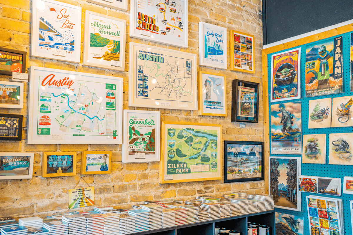 A colorful display of assorted travel posters on a brick wall in a shop