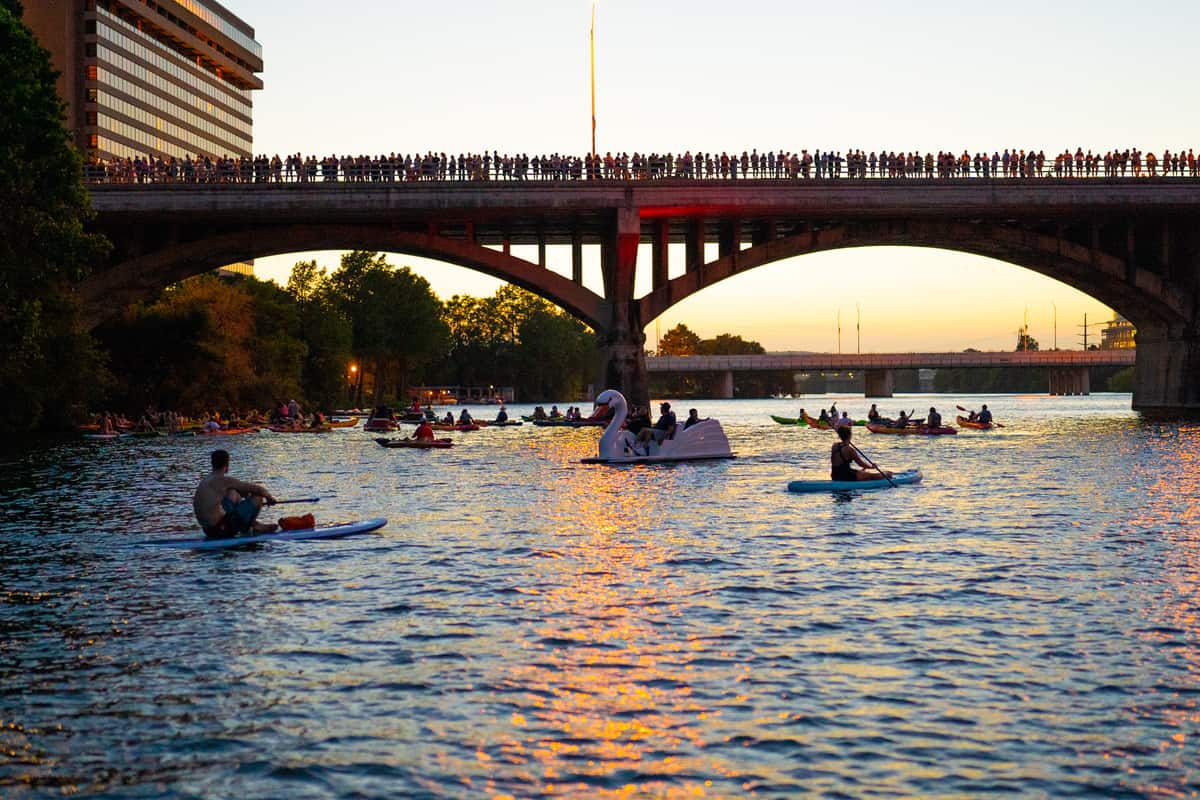 Canoes on Lady Bird Lake at sunset with Congress Avenue Bridge