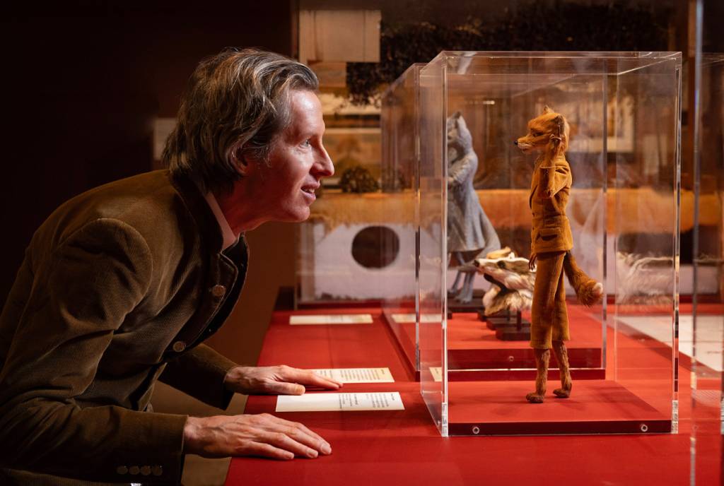 Image shows Wes Anderson looking at an encased sculpture of the Fantastic Mr. Fox character. 