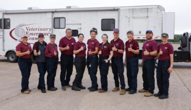 A group of people standing in front of a Veterinary Emergency Team mobilization trailer.