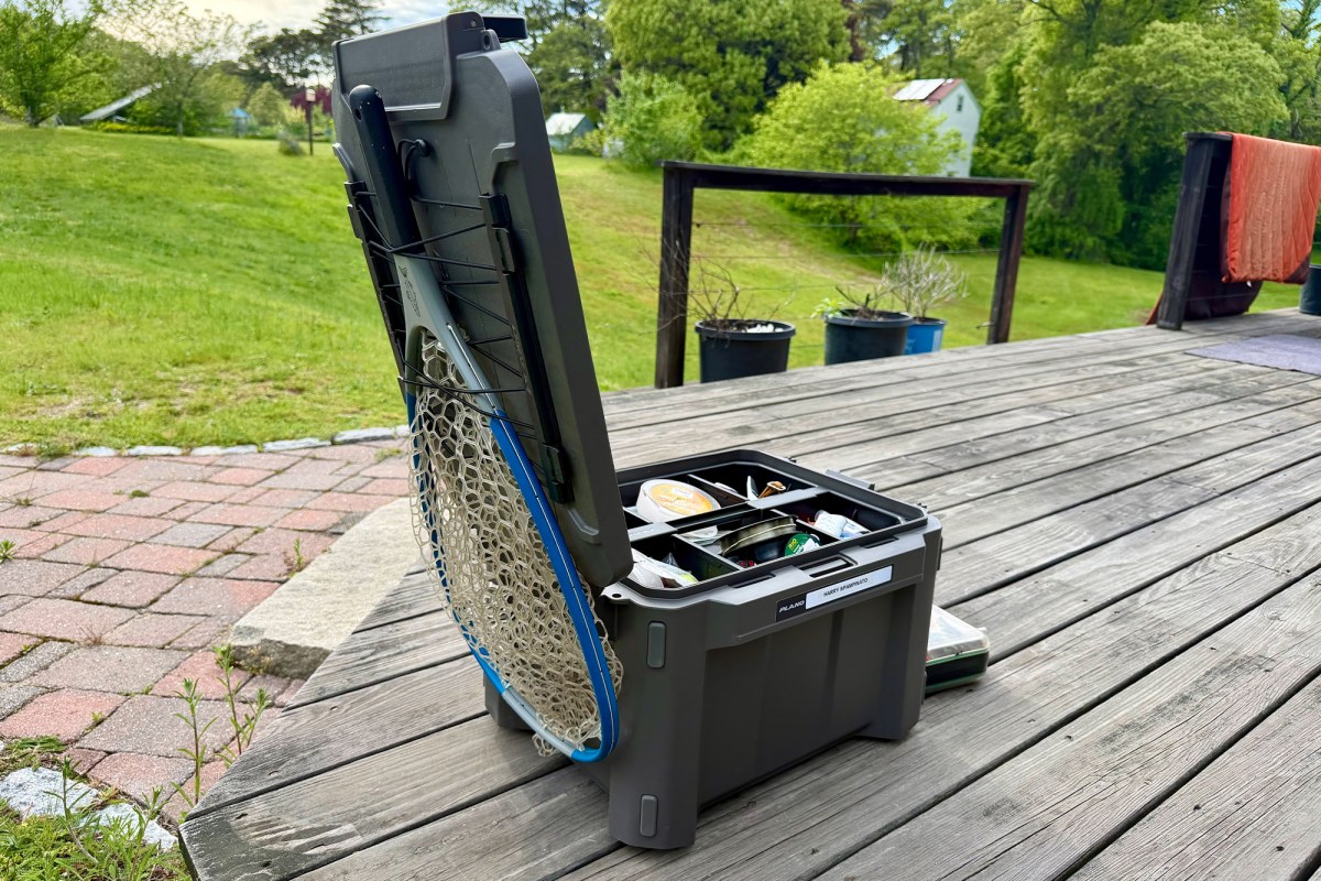 Open Plano box with fishing gear and a net strapped to the lid