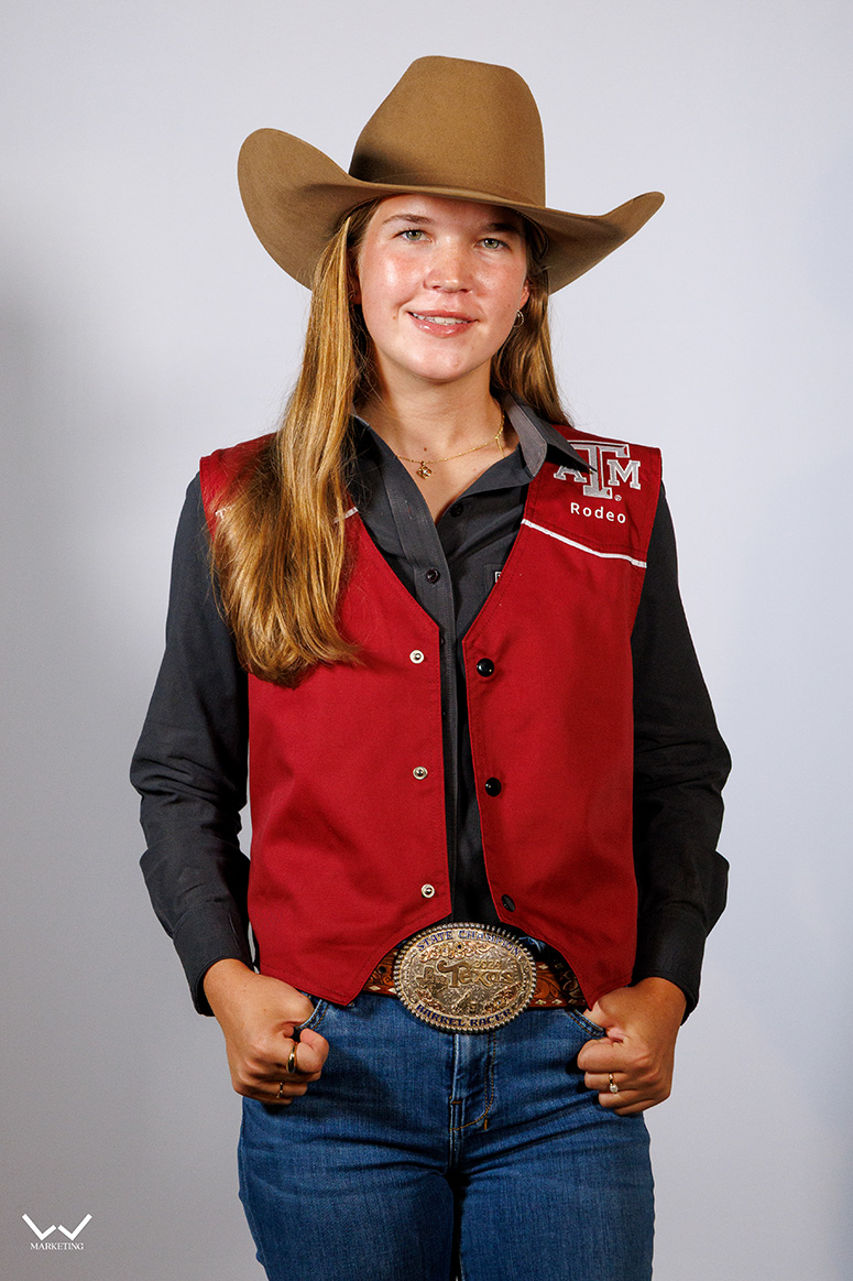 a smiling woman in a maroon vest and brown hat