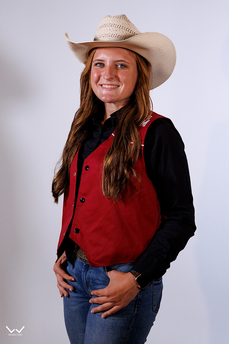 a smiling woman in a maroon vest and white hat