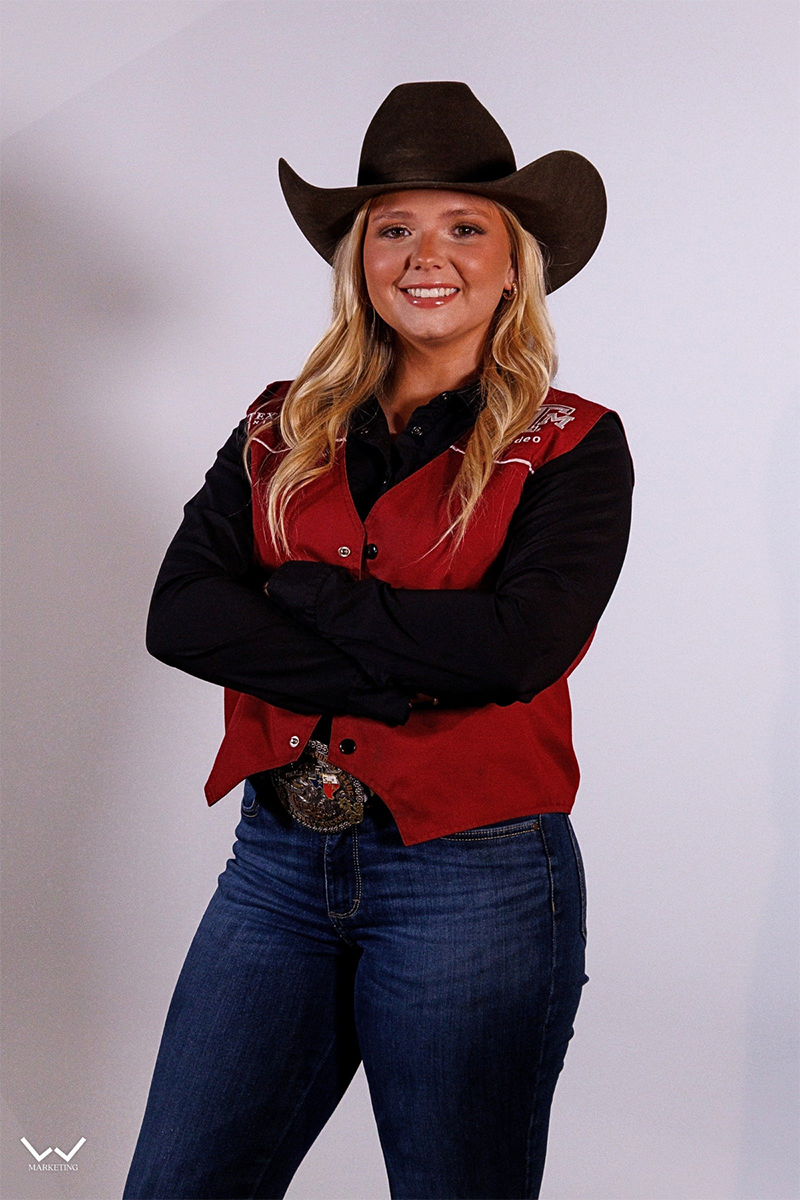 a smiling woman in a maroon vest and black hat