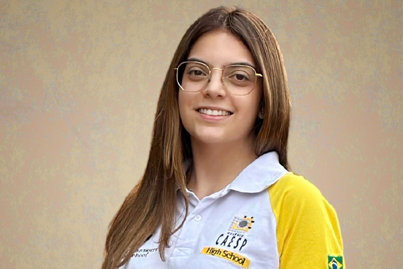 Julia Neme poses for a photo in her yellow and white high school polo shirt.