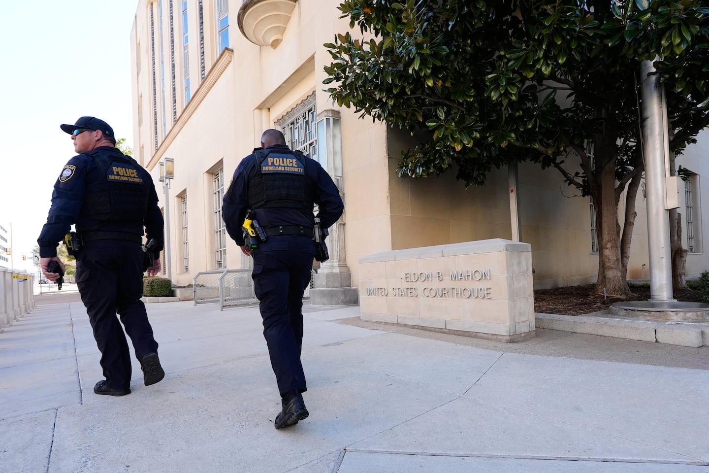 Officers with the Department of Homeland Security walked on the sidewalk outside the Eldon B. Mahon US Courthouse during a trial for people connected to a 2025 shooting outside an ICE detention facility, in Fort Worth, Texas, in March.