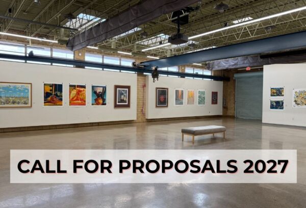 An art gallery with clerestory windows and exposed brick, with paintings on plasterboard walls and a line reading "Call for Proposals 2027."
