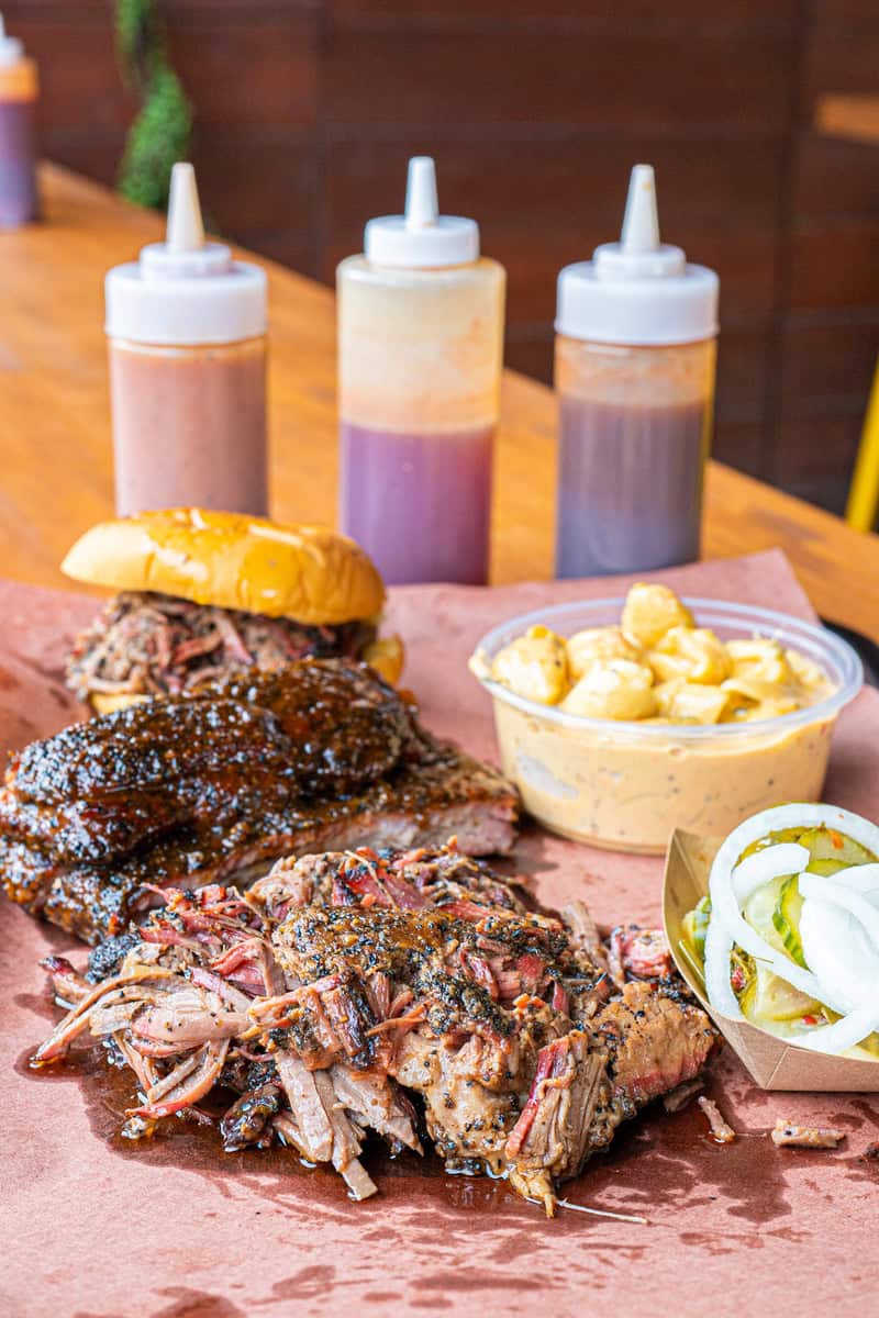 Barbecue brisket with sauce, sandwich, mac and cheese, salad, and condiments